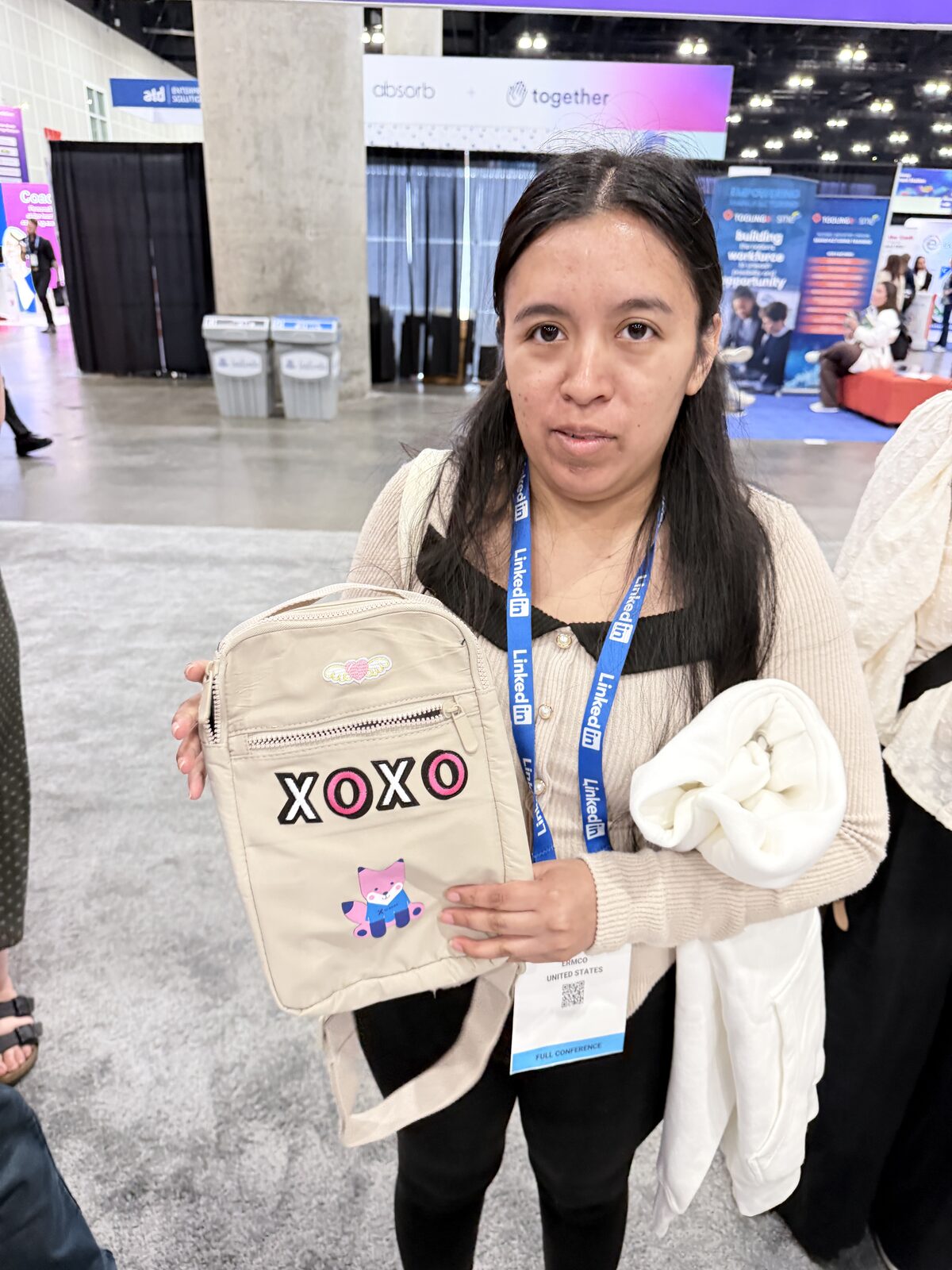 Guest showing off a crossbody bag finished with chenille letter patches at a trade show