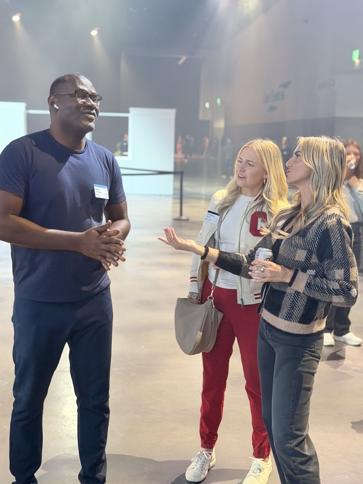 Three guests chatting on an open event floor near the customization stations