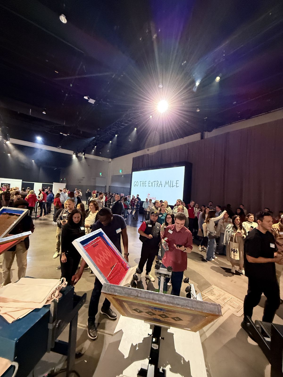 Wide view of a large venue floor with customization stations and hundreds of guests